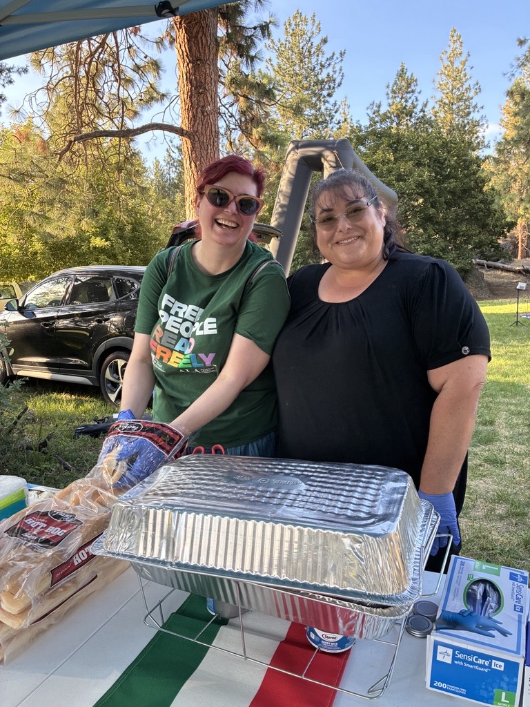 Two volunteers at the Minnehaha National Night Out serving hotdogs and smiling.